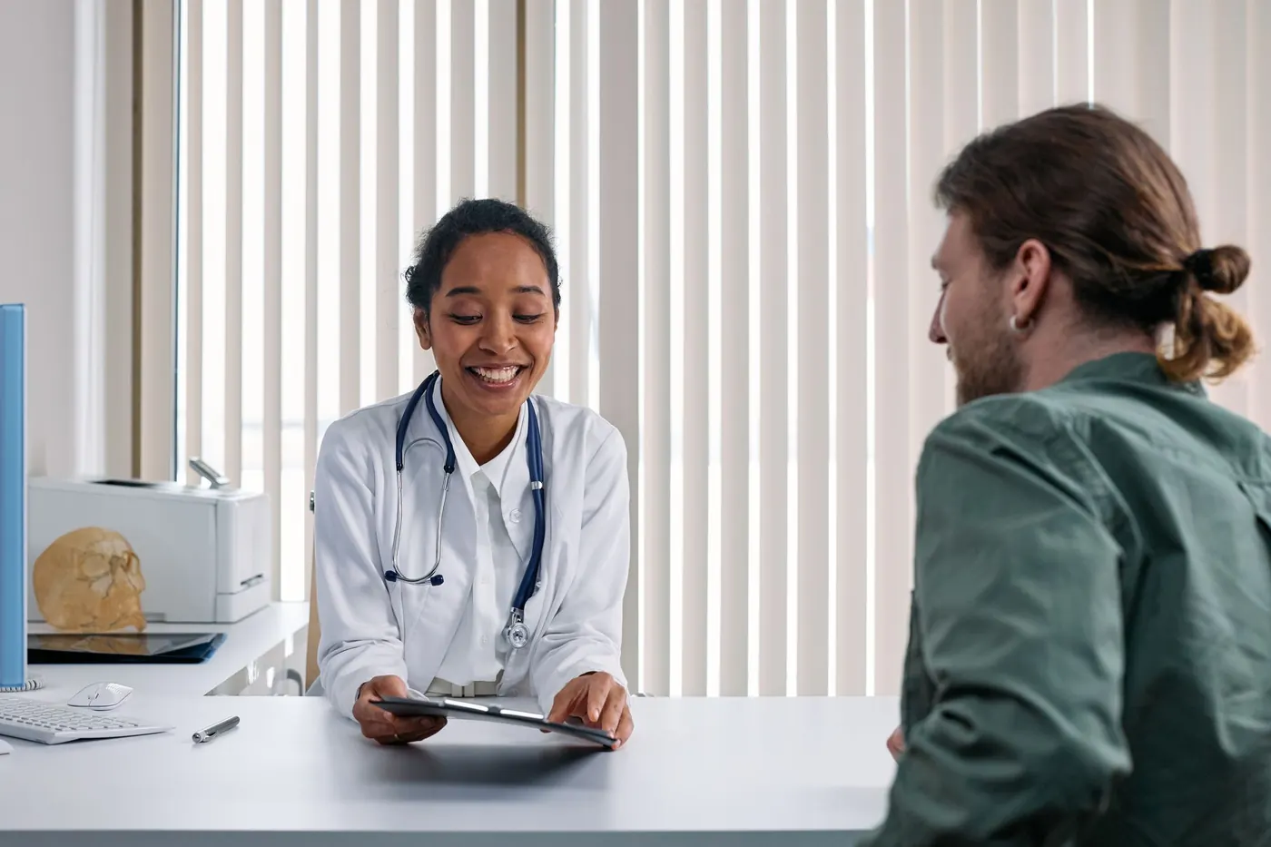 Ärztin bespricht im Sprechzimmer des MVZ Berlin freundlich die Befunde mit einem Patienten (Symbolbild)